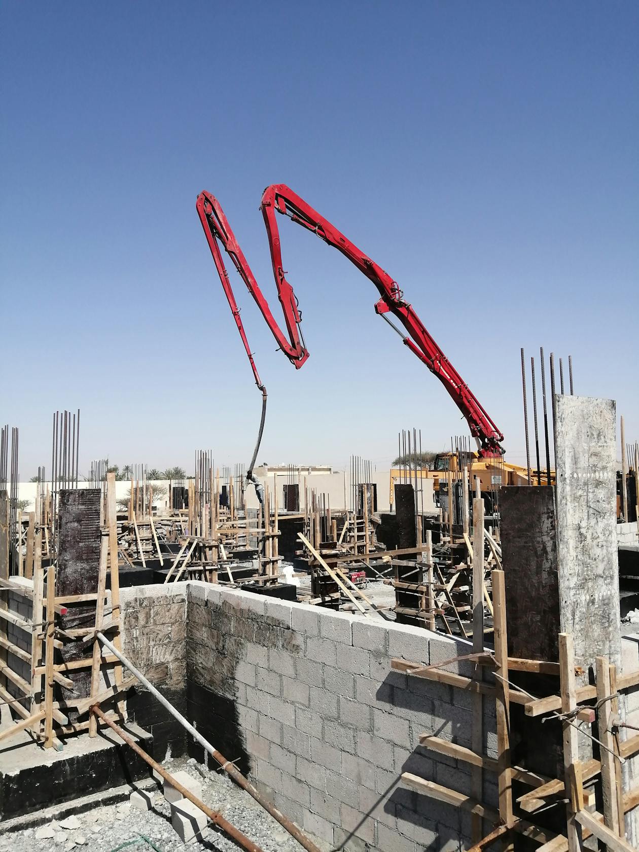 Sunlit construction site with concrete pump equipment and long-reach setup