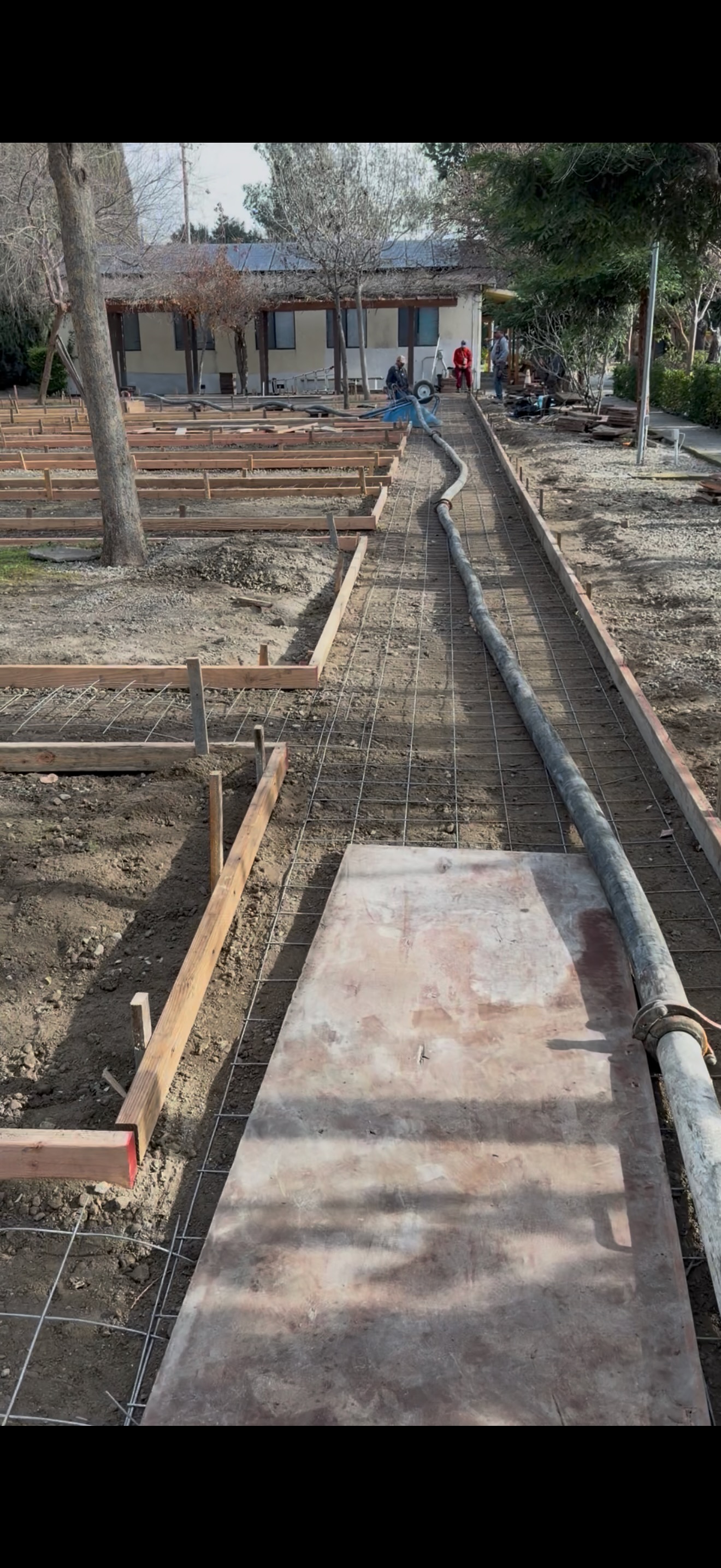 Long concrete hose running over dirt and rebar