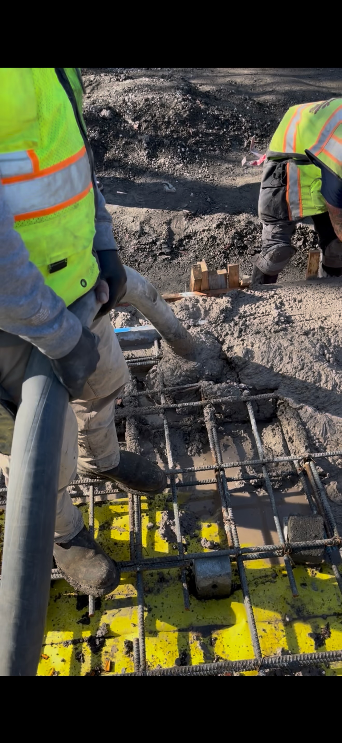 Workers pouring concrete into rebar grid